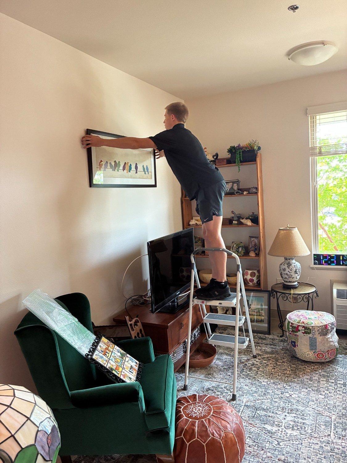 Settled in Texas team member hanging a framed picture while setting up a new home