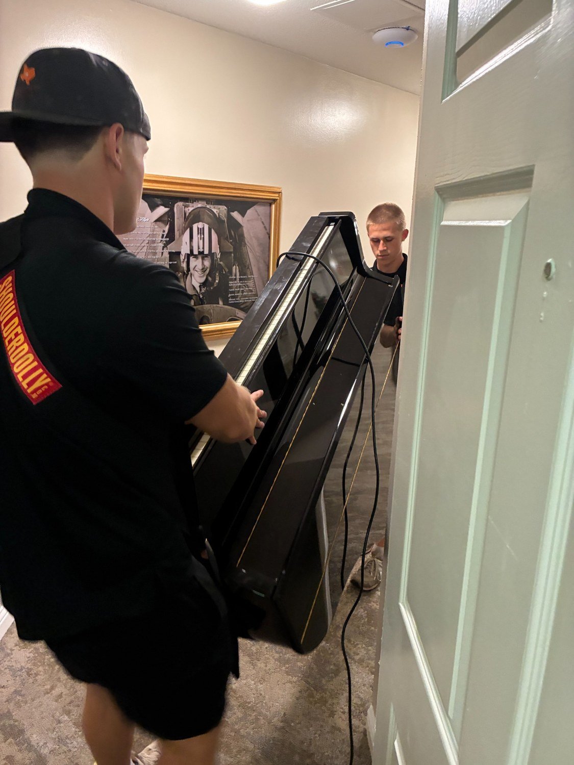 Two Settled in Texas team members carefully moving an upright piano